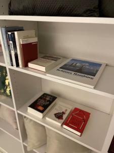 une étagère avec des livres et autres livres dans l'établissement JPP 1- Zimmer Apartment in Hamburg Farmsen Berne SELF CHECK-IN, à Hambourg