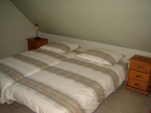 1 cama blanca con 2 almohadas y una mesita de noche en De Kleen Meulen - max 6pers, en Lummen
