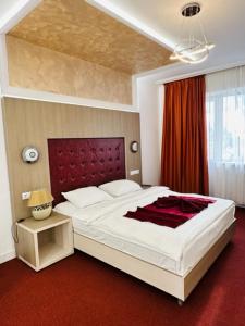 a bedroom with a large bed and a red carpet at Hotel Bulevard Prestige in Slatina