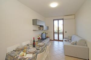 eine Küche und ein Wohnzimmer mit einem Tisch und einem Sofa in der Unterkunft Appartamento Magenta - Gardagate in Moniga
