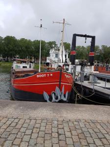 Boathotel Rotterdam Seven في روتردام: يتم رسو قارب احمر في المرسى