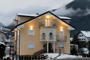 a yellow house with a balcony in the snow at Ferienwohnung Schönblick in Weissenbach am Lech