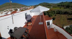 un balcón de una casa con una mesa y una sombrilla blanca en CASA APARTAMENTO TERRAZAS DE ALGODONALES, en Algodonales