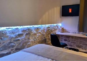 ein Schlafzimmer mit einer Akzentwand aus Stein und einem Stuhl in der Unterkunft AVALON Luxury Suites in Ermoupoli