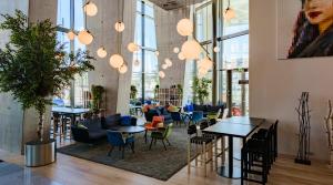 a lobby with tables and chairs and windows at Clarion Hotel Helsinki in Helsinki