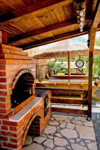 un patio al aire libre con horno de ladrillo y sombrilla en Vila Bucuria Corbu, en Corbu