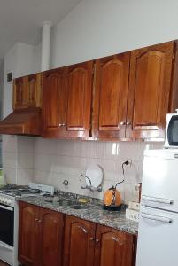 cocina con armarios de madera y nevera blanca en Departamentos San Rafael Mendoza en San Rafael