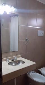 y baño con lavabo, espejo y aseo. en Departamentos San Rafael Mendoza en San Rafael