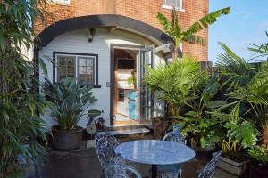 a patio with a table and chairs in front of a house at The Cabana - a romantic seaside getaway and garden in Ryde