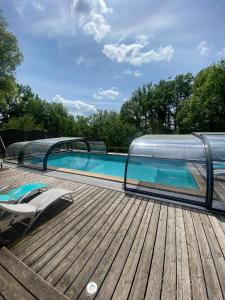 a swimming pool on a wooden deck with a chair next to it at La Truffière du Vignou in Archignac
