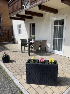 a patio with a table and chairs and flowers at Ferienwohnung "Beim Dôneslar" in Bad Oberdorf