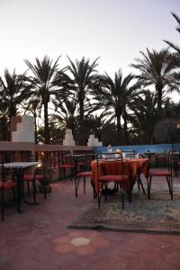 d'une terrasse avec des tables, des chaises et des palmiers. dans l'établissement Prends Ton Temps, à Zagora