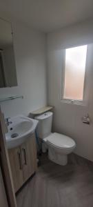 a bathroom with a toilet and a sink and a window at Mobil Home Palmiers 1 in Valras-Plage
