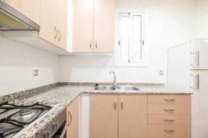 cocina blanca con fregadero y fogones en Consell Cent apartment I 3 dormitorios Eixample, en Barcelona