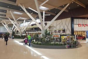 a shopping mall with people walking around a flower display at Cozy apartment near Lõunakeskus with home cinema in Tartu