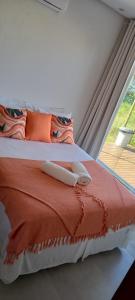 a bedroom with a bed with orange pillows and a window at Shaqat Barra Flat in Barra Grande