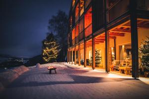 a building with a fire pit in the snow at night at Gailerhof Hotel B&B Superior in Monguelfo