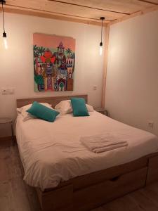 a bed with two pillows and a painting on the wall at Le Gîte les NUZ ( parc du château de Keroüartz) in Lannilis