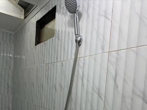 a shower in a white tiled bathroom at Penginapan Violet Doorz Syariah in Banjarbaru +15 photos