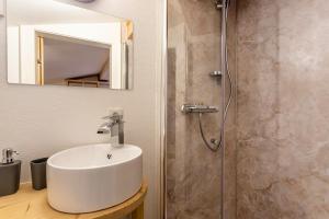 La salle de bains est pourvue d'un lavabo blanc et d'une douche. dans l'établissement Bergwelt B, à Niederau