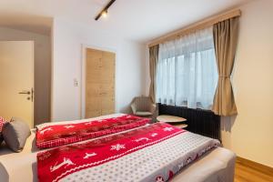 Schlafzimmer mit einem Bett mit roter Bettwäsche und einem Fenster in der Unterkunft Bergwelt A1 in Niederau