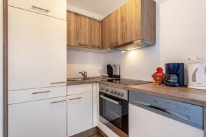 eine Küche mit weißen Geräten und Holzschränken in der Unterkunft Bergwelt C in Niederau