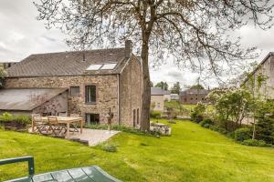 une maison en pierre avec une table de pique-nique dans une cour dans l'établissement La Bergerie, à Gedinne