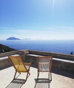Dos sillas sentadas en una cornisa con vistas al océano en Alicudi Giardino dei Carrubi- al gradino 365, en Alicudi