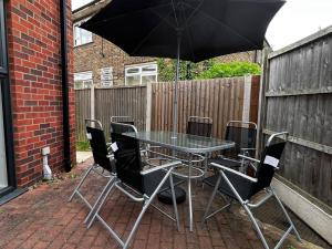 a table with chairs and an umbrella on a patio at Beautiful 4-Bed House in Lincoln- close to Centre in Lincoln