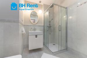W łazience znajduje się prysznic, umywalka i lustro. w obiekcie Glow Apartments, Gdańsk Śląska 12 w Gdańsku