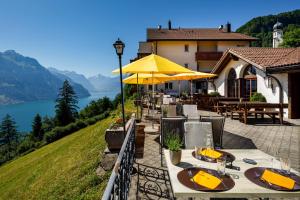 ein Restaurant mit Tischen und gelben Sonnenschirmen und einem See in der Unterkunft Hotel und Naturhaus Bellevue in Seelisberg
