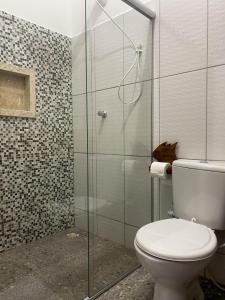 a bathroom with a toilet and a glass shower at Apartamentos Terra Mar in Trancoso