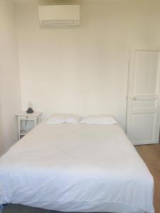 a white bed in a white bedroom with a white door at T2 neuf tout équipé, climatisé in Marseille