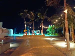 a lit up sign at night with palm trees at Sisal Brisa de Mar in Sisal