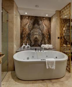 Triumph Luxury Hotel في القاهرة: حوض استحمام في الحمام بجدار حجري