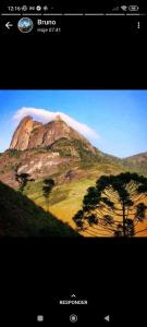 une photo d'une montagne avec un arbre au premier plan dans l'établissement Encanto da Pedra, à Visconde de Mauá