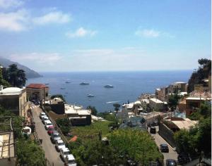 une ville avec des voitures garées dans une rue et l'océan dans l'établissement Ludovica Tipo C, à Positano