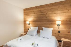 Schlafzimmer mit einem großen weißen Bett und Holzwänden in der Unterkunft Appartement Périade - Welkeys in Megève