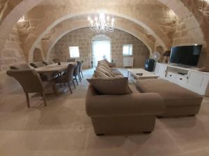 ein Wohnzimmer mit einem Sofa und einem Tisch mit Stühlen in der Unterkunft Farmhouse Villa in Gozo with large pool & garden in Birbuba