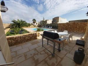 einen Grill auf einer Terrasse neben einem Pool in der Unterkunft Farmhouse Villa in Gozo with large pool & garden in Birbuba