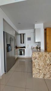 cocina con armarios blancos y nevera de acero inoxidable en Apartamento en Lujoso Edificio H2 Plaza Bocagrande, en Cartagena de Indias