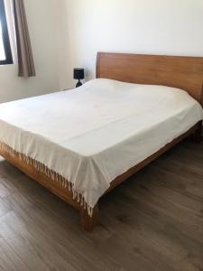 uma cama com uma estrutura de madeira e um lençol branco em Maison familiale à Ile Maurice em Mahébourg