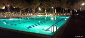 a swimming pool lit up at night with lights at Signora Ruth - Aprilia Residence in Aprilia Marittima