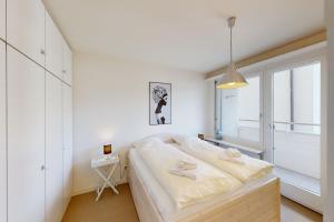 a white bedroom with a large bed and a window at Au Reduit 401 in St. Moritz