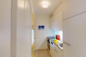 a kitchen with white cabinets and a sink at Au Reduit 401 in St. Moritz