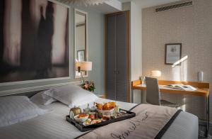 a hotel room with a tray of food on a bed at Hotel Litteraire Le Swann, BW Premier Collection in Paris
