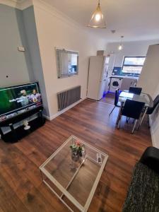 a living room with a tv and a glass table at Beautiful Modern Apartment on Wick Lane in London