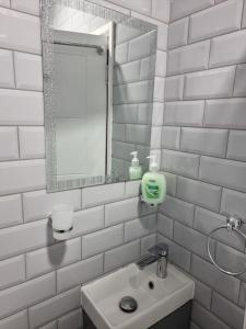 a white tiled bathroom with a sink and a mirror at Beautiful Modern Apartment on Wick Lane in London