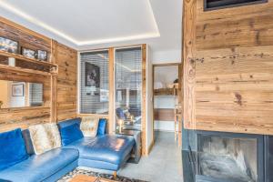 a living room with a blue couch and a fireplace at Superb ski-in apartment in Megève - Welkeys in Megève
