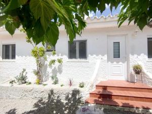 una casa blanca con plantas delante en La Villa Romantica Résidence de vacances Les Tres Cales Espagne, en Les tres Cales